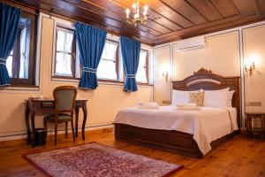 a bedroom with a bed with blue curtains and a desk at RAHAT Guest House in Old Town - Free Private Parking in Plovdiv