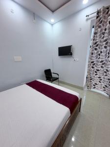 ein Schlafzimmer mit einem Bett und einem Fernseher an der Wand in der Unterkunft Hotel Mayaa Inn in Chupra
