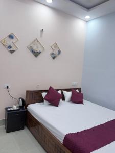 ein Schlafzimmer mit einem großen Bett und lila Kissen in der Unterkunft Hotel Mayaa Inn in Chupra