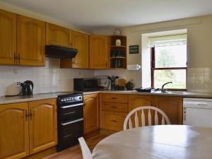 a kitchen with wooden cabinets and a table in it at Port-An-Eillean in Feorlean