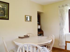 a dining room with a white table and chairs at Port-An-Eillean in Feorlean