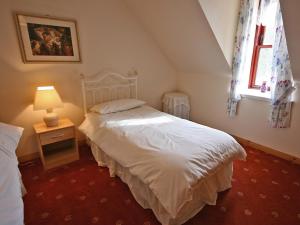 a bedroom with a white bed and a window at Port-An-Eillean in Feorlean