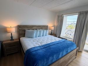 a bedroom with a bed with a blue blanket and a window at Beachcomber Motel in Ocean City +27 photos