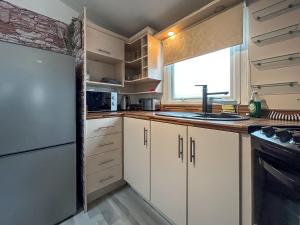 a kitchen with white cabinets and a sink and a window at Uk51412 - The Haven in Brechin