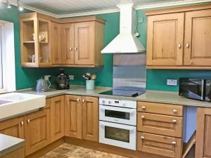 a kitchen with wooden cabinets and a white stove top oven at Laxdale Cottage in Leverburgh +7 photos