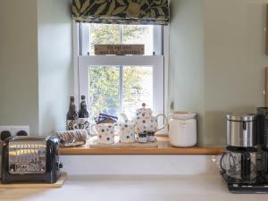 a kitchen counter with a window and a shelf with dishes at Lawson's Studio in Redmire +13 photos