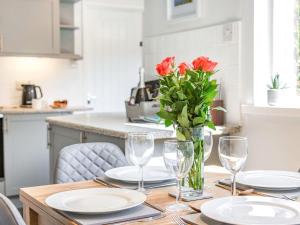 a table with plates and glasses and a vase with red flowers at Hotspur View in Alnwick