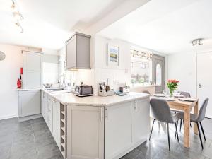 a kitchen with white cabinets and a table and chairs at Hotspur View in Alnwick