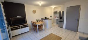 a living room with a television and a kitchen at Appartement T2 lac Léman in Publier +8 photos