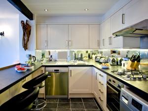 a kitchen with white cabinets and stainless steel appliances at 3 Torwood Gables in Torquay