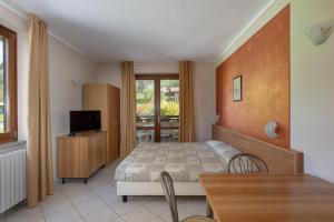 a bedroom with a bed and a table and a television at Hotel Residence La Pertica in Tremosine Sul Garda