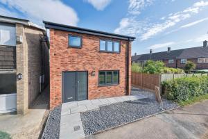 a brick house with a black door on a street at Modern Cambridge North Flat in Milton