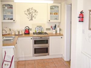 a kitchen with white cabinets and a stove at Watchkeeper's Cottage in Mundesley