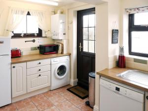 a small kitchen with a washer and dryer in it at Watchkeeper's Cottage in Mundesley
