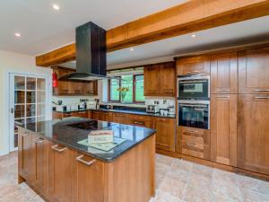 a large kitchen with wooden cabinets and a counter top at Rhiew Banc in Aberhafesp