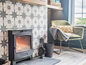 a living room with a fireplace and a chair at Pennant in Llanerfyl