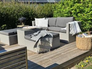 a couch and a table on a wooden deck at Gästhus i lummig trädgård - i idylliska Örum in Löderup