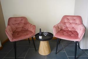 two pink chairs and a table with a wine glass at Agriturismo Cascina Sciulun in Monforte dʼAlba