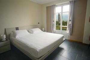 a bedroom with a white bed and a window at Agriturismo Cascina Sciulun in Monforte dʼAlba