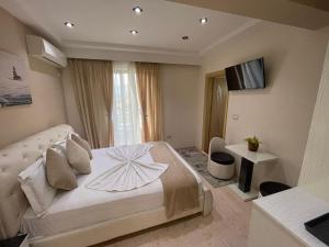 a bedroom with a white bed and a television at Hotel Selfo in Gjirokastër