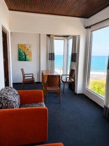 a living room with an orange couch and a table and windows at Villa Yuvin in Matara