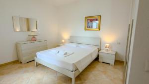 a bedroom with a white bed and two night stands at Gigi's House in Cala Gonone