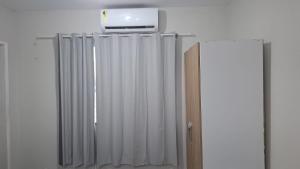 a room with white curtains and a refrigerator at my sweet place 33 in São Luís
