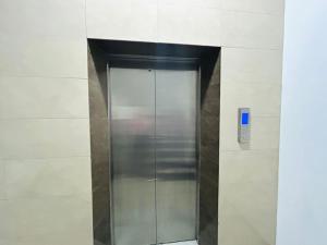 a metal elevator in a building with a blue button at Kalubowila Rooms in Dehiwala