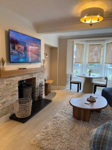 a living room with a fireplace and a tv at 15 By The Shore in Caol