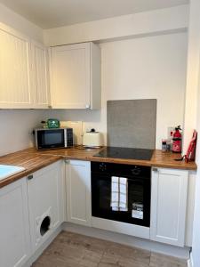 a kitchen with white cabinets and a black oven at 15 By The Shore in Caol