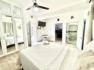 a white bedroom with a bed and a ceiling fan at Mi Refugio 1 in Río San Juan