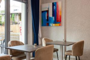 two tables in a room with chairs and a painting at Hotel Villa Irene & Spa in Rimini