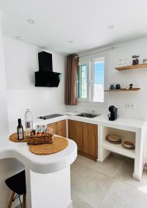 a white kitchen with a counter and a table at Irini's House Sunbeam in Dhragoulás