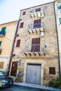 a tall brick building with windows and a balcony at Bed & Breakfast Il Castellino in Santo Stefano di Camastra