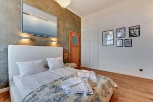 ソポトにあるLion Apartments - Family Stayの白い大型ベッドと壁が備わるベッドルーム1室が備わります。
