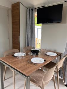 a dining room table with chairs and a television at Camping Le Neptune in Lanloup