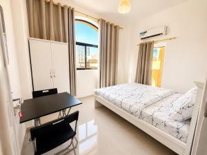 a bedroom with a bed and a desk and a window at Flora Residence in Abu Dhabi