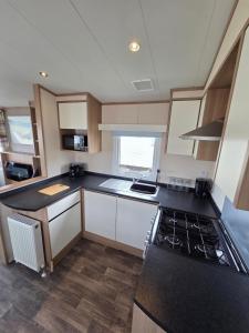 a kitchen with white cabinets and a black counter top at The Cavern Retreat in Rhyl