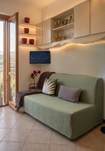 a green couch in a living room with a window at Elegant Penthouse LA BALCONATA - Wellness Retreat & Castle View in Tabiano