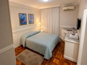 a small bedroom with a bed and a desk at Hotel Bruggemann in Florianópolis
