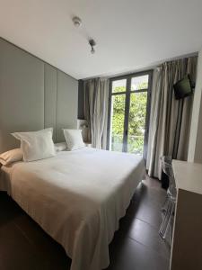 a bedroom with a large white bed and a window at Hotel Avenida 31 in Marbella