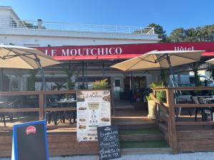 a restaurant with tables and umbrellas in front of it at Le Moutchico in Lacanau