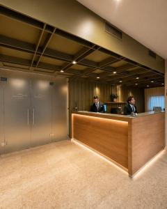 two men sitting at a reception desk in an office at Hotel La Costiera in Varcaturo