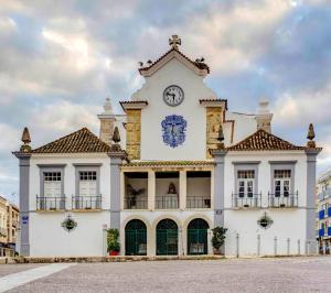 a large white building with a clock on it at Hotel Cidade de Olhão in Olhão
