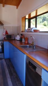 a kitchen with blue cabinets and a sink and a window at Das Glashaus in Curacautín