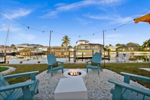 a patio with two blue chairs and a fire pit at Casa Azul - Waterfront Villa with Pool & Dock in Marco Island