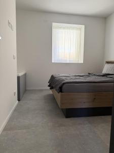 a white bedroom with a bed and a window at Z&N Apartment in Levico Terme