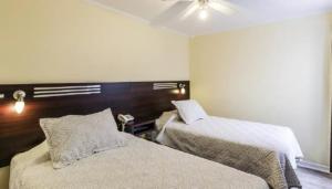a bedroom with two beds and a ceiling fan at Hotel Costa Marfil Baquedano in Antofagasta