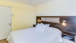 a bedroom with a white bed with a wooden headboard at Hotel Costa Marfil Baquedano in Antofagasta