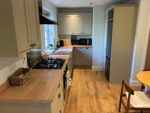 a kitchen with white cabinets and a stove top oven at Country Cottage with moat in Ingatestone